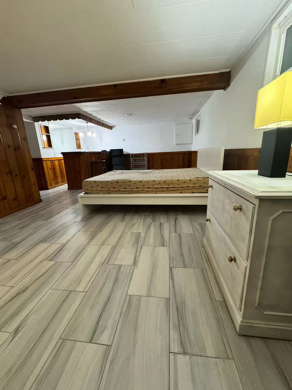 Bedroom with tile floor and kitchenette beyond
